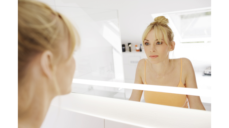 Woman looking at her mirror image in the bathroom