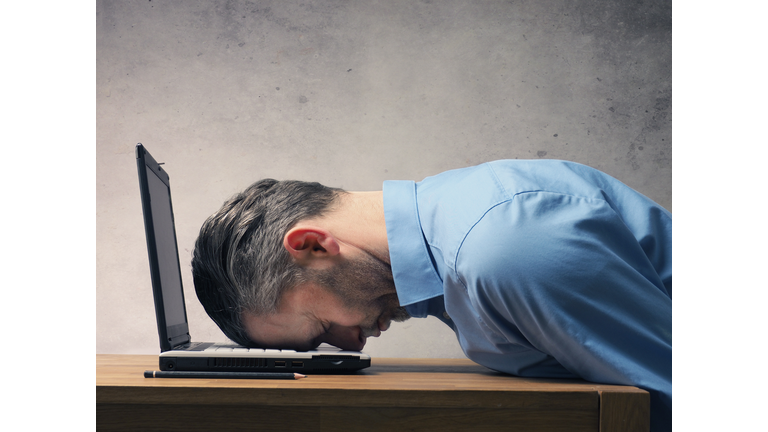 Close-Up Of Tired Man Leaning By Laptop At Desk