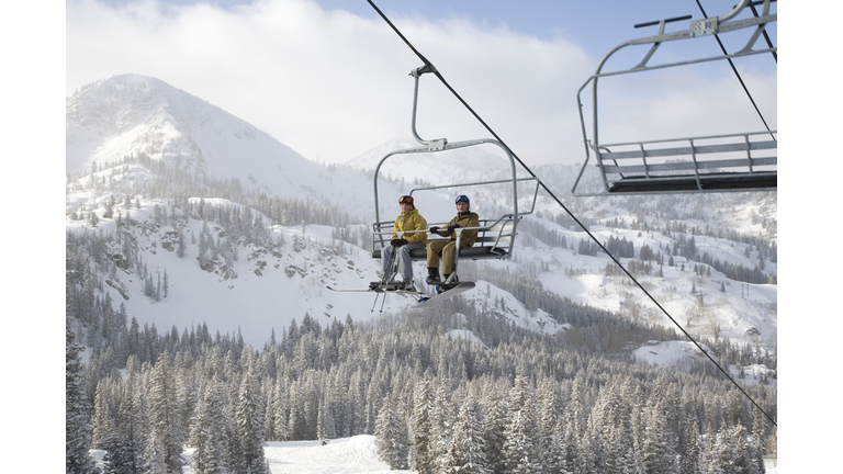 USA, Utah, teenage girl and boy (13-16) sitting on ski lift at Brighton ski resort