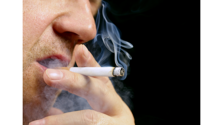 Senior male smoking cigarette on black background