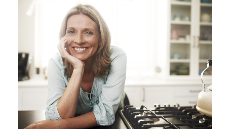 Happy woman leaning on kitchen counter