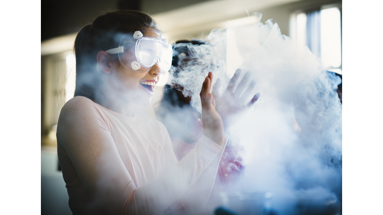 Smiling girl gesturing while surrounded by smoke