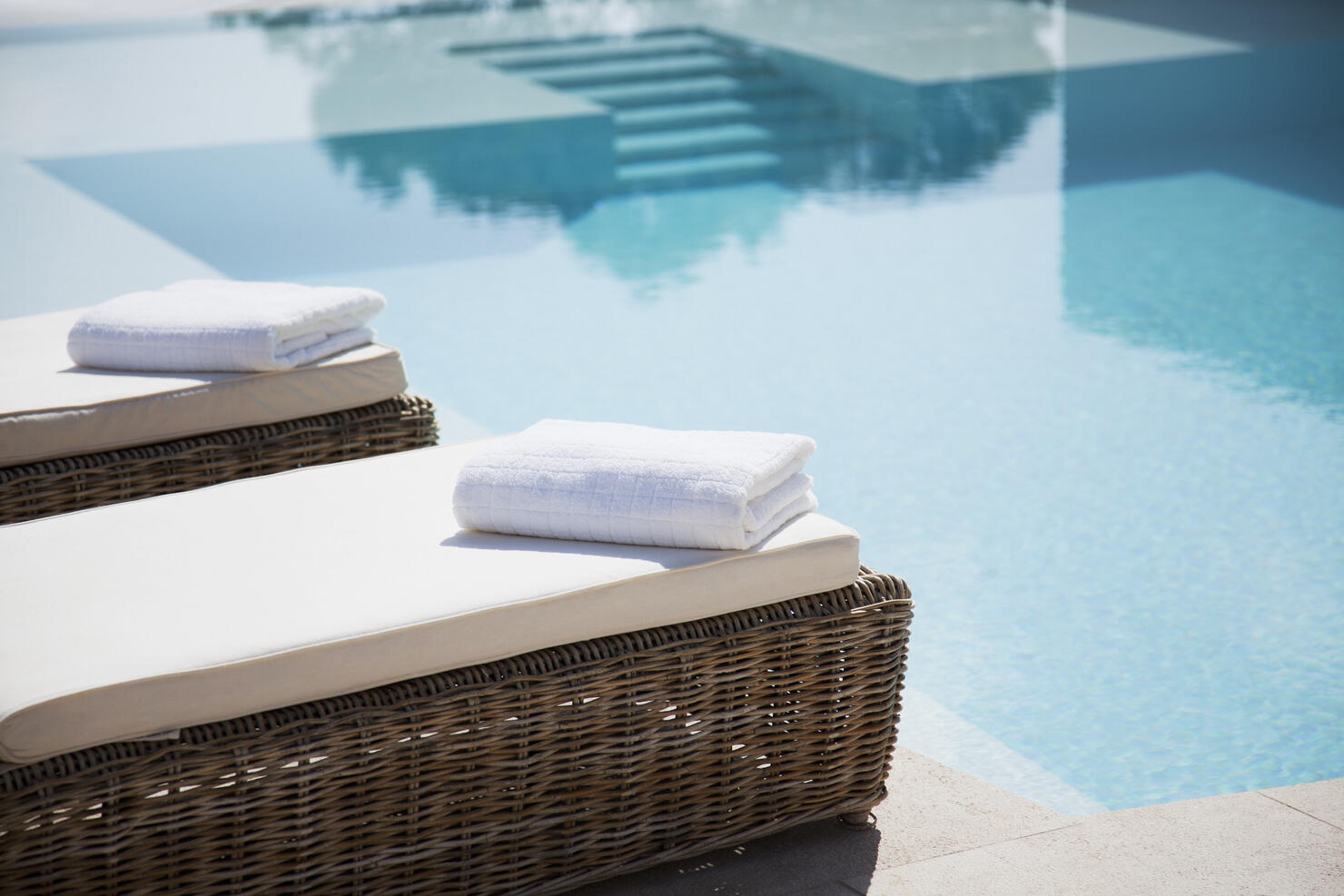 Folded towels on lounge chairs beside pool