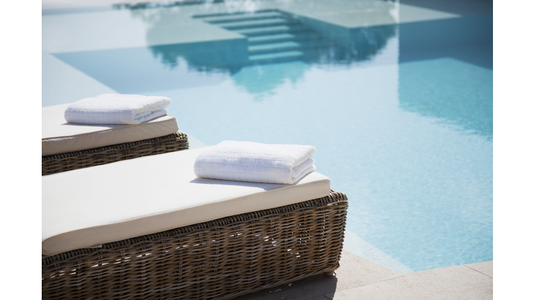 Folded towels on lounge chairs beside pool