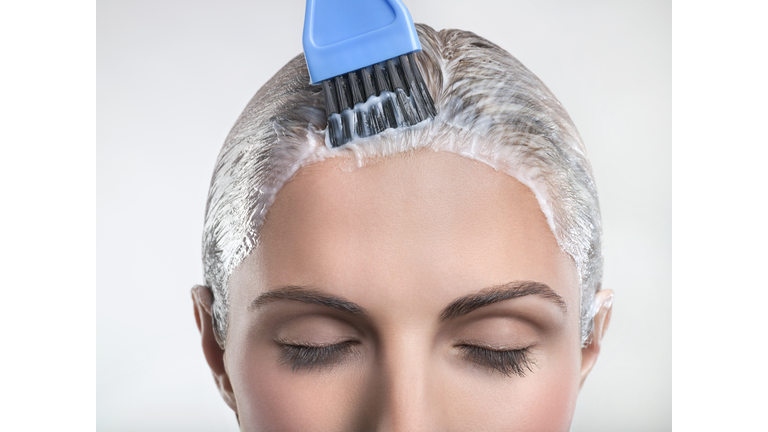 Young woman applying hair color