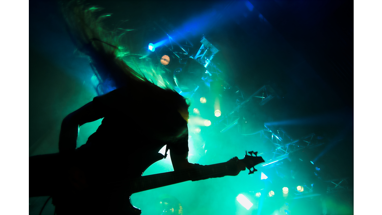 Silhouette of heavy metal guitar player performing live