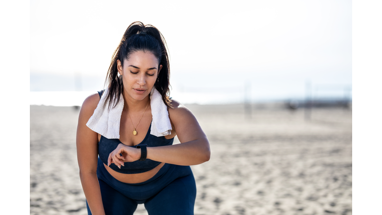 Woman checking her fitness progress after workout at the beach