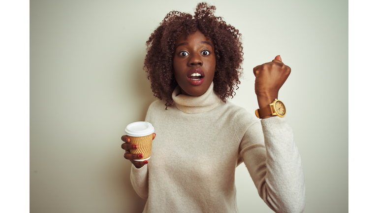 Young african afro woman holding cup of coffee standing over isolated white background annoyed and frustrated shouting with anger, crazy and yelling with raised hand, anger concept