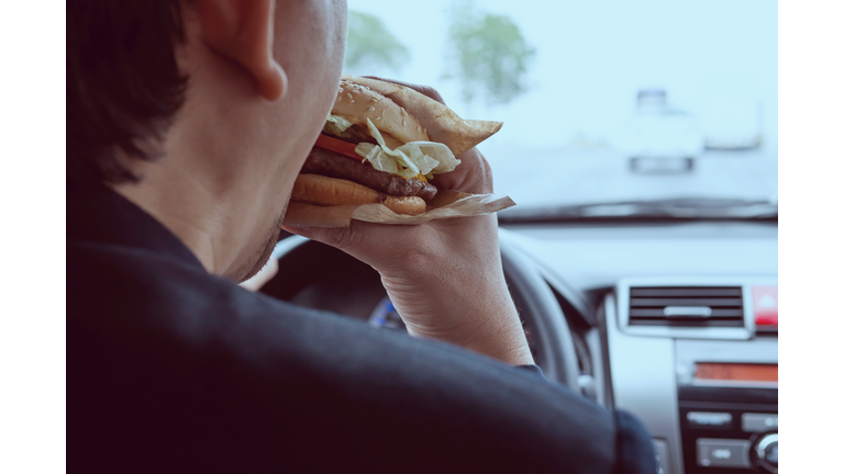 Cropped Image Of Man Eating Burger In Car