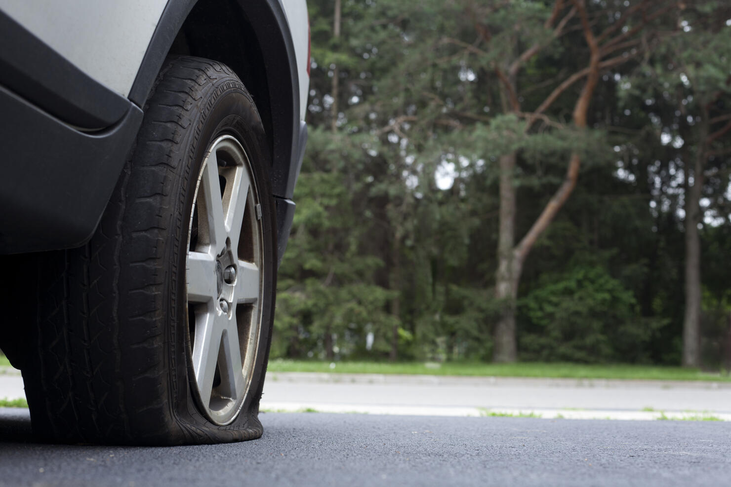 Close-up photo of a flat tire on a car on a road