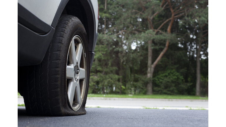 Close-up photo of a flat tire on a car on a road