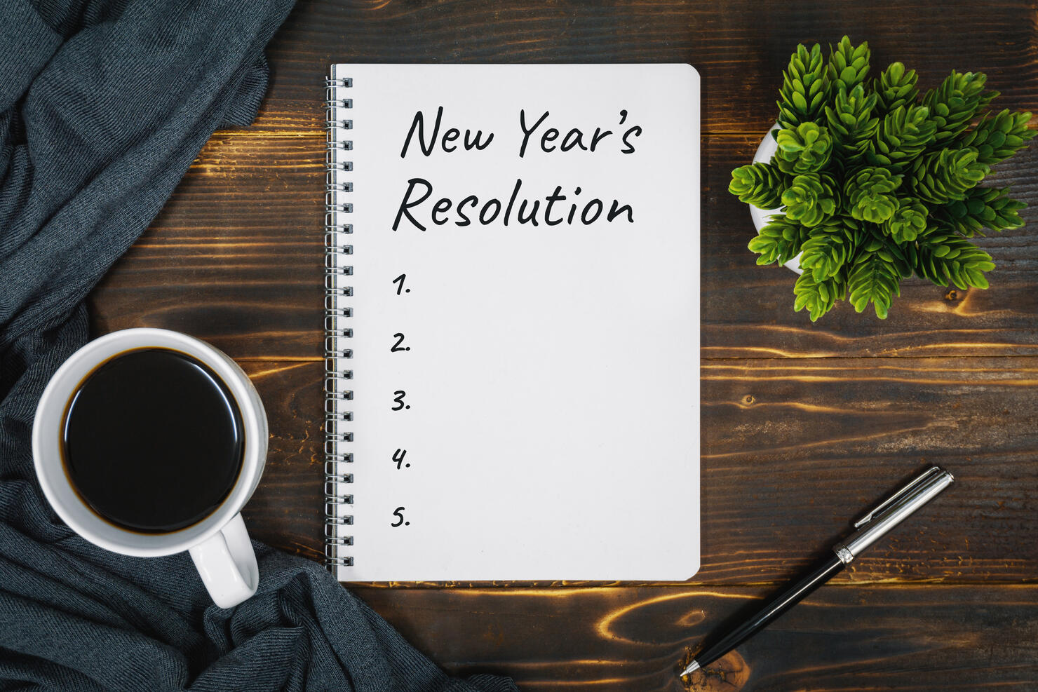 New Year's Resolution on Notebook Page Over Rustic Wood