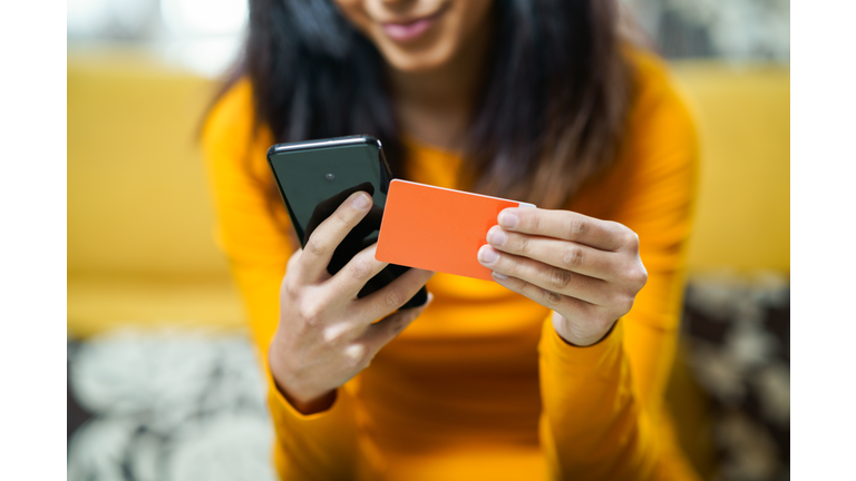 Midsection Of Woman Using Mobile Phone While Holding Credit Card