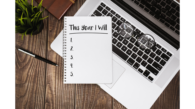 New Year Resolutions on Notebook With Laptop Over Wood Desk.