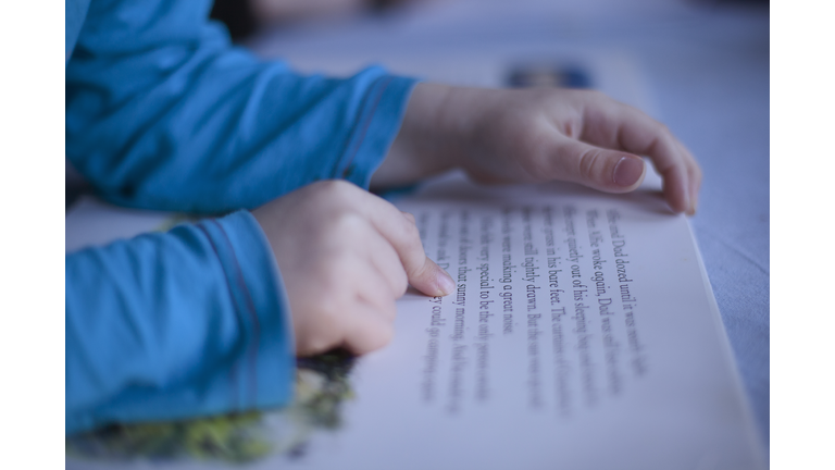 close up boys fingers pointing to words in book