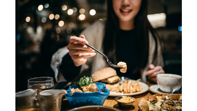 Smiling young woman enjoying her meal and sharing her food in a restaurant