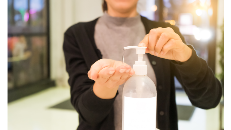 Female using alcohol gel as hand sanitizer at shopping center for prevent the spread of germs and bacteria and avoid infections corona virus. Hygiene concept