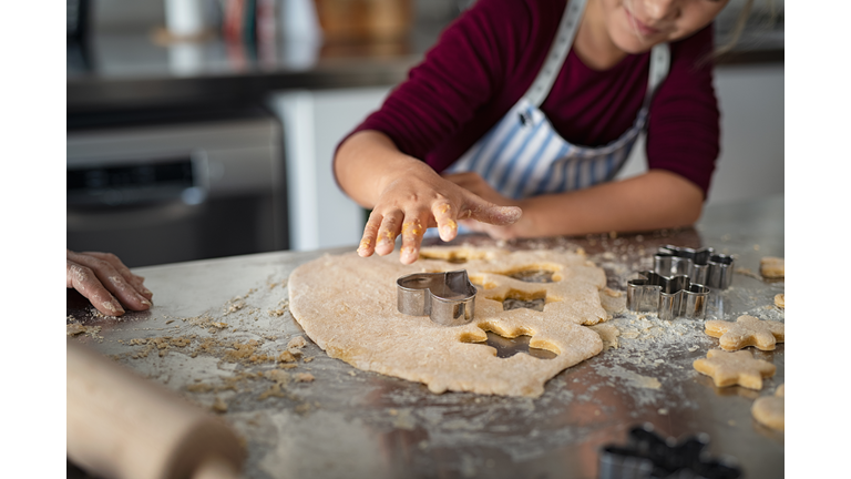 Child cutting dough for christmas cookies