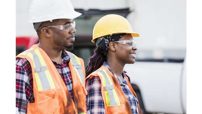 Female construction worker and coworker wearing hardhats