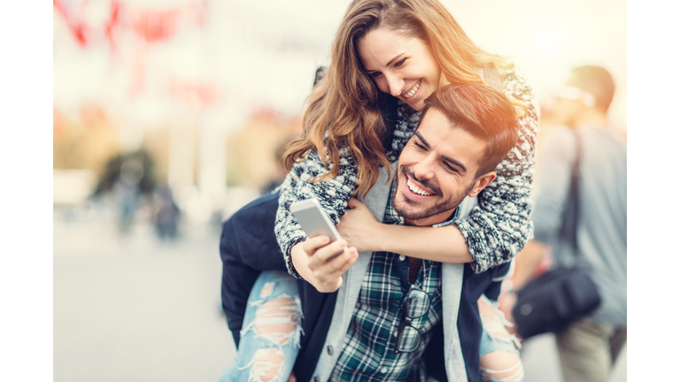 Man carrying his girlfriend on piggyback for selfie