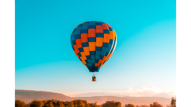 Low Angle View Of Hot Air Balloon Flying In Mid-Air Against Clear Blue Sky