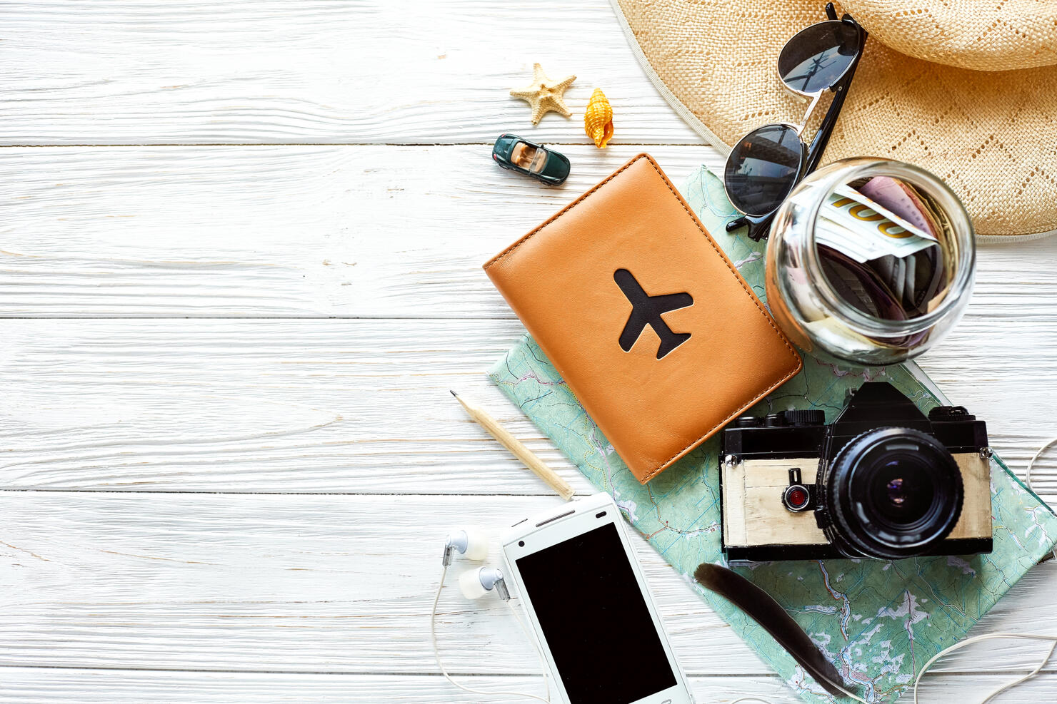 summer travel wanderlust concept, space for text, flat lay. map camera sunglasses  passport money phone hat shells car toy on white wooden background top view. hello holiday, planning vacation