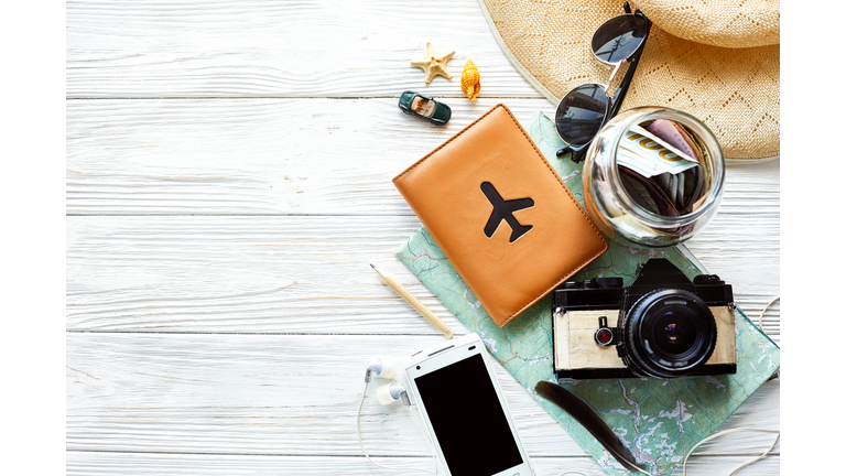 summer travel wanderlust concept, space for text, flat lay. map camera sunglasses  passport money phone hat shells car toy on white wooden background top view. hello holiday, planning vacation