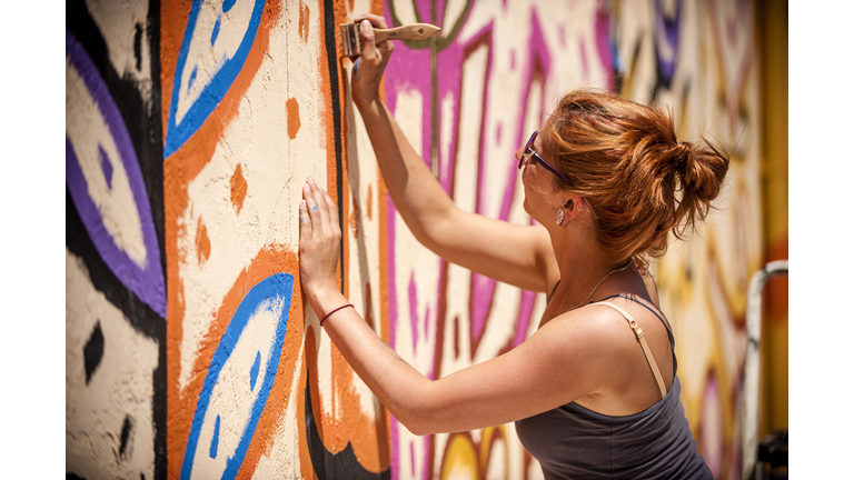 Caucasian woman painting mural on wall