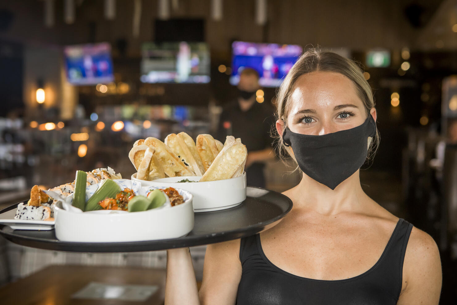 Waitress carrying a tray with food.