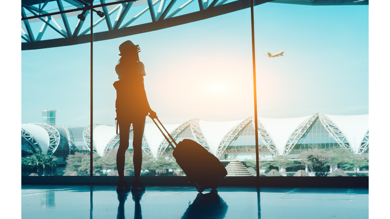 Silhouette Woman With Luggage Standing In Airport