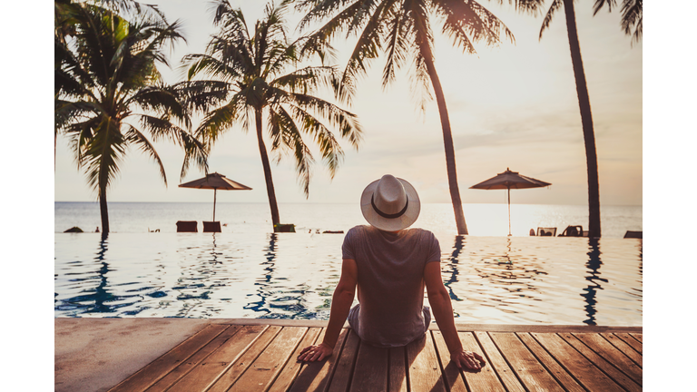 Holidays, tourist relaxing in luxury beach hotel near luxurious swimming pool.