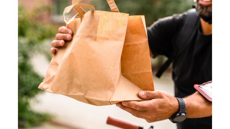 A delivery man is using a bike to transport food in the city