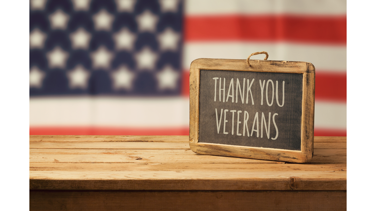 Veterans day background with chalkboard on wooden table and USA flag