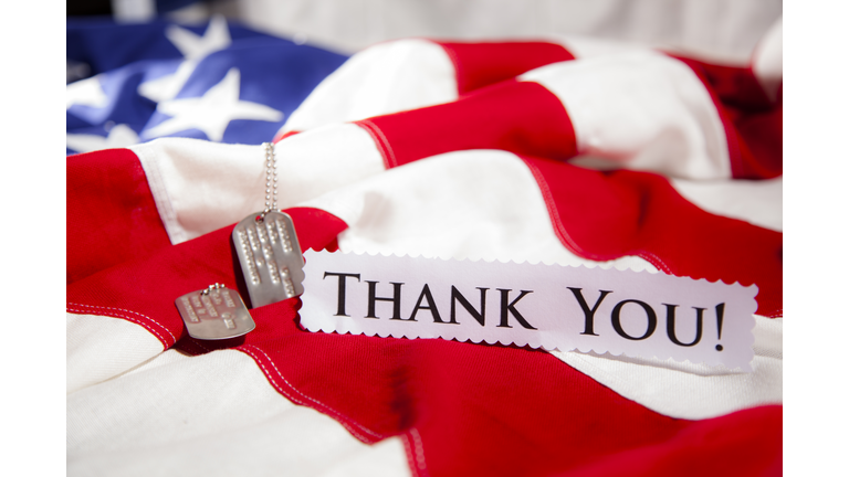 Military dog tags beside "Thank You" note. American flags. Patriotism.