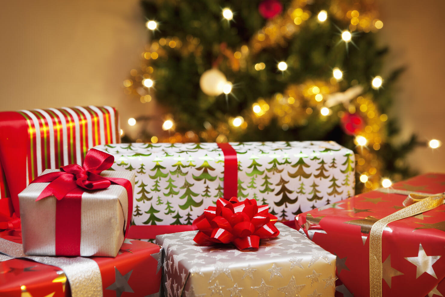 Group of Christmas gifts in front of tree.