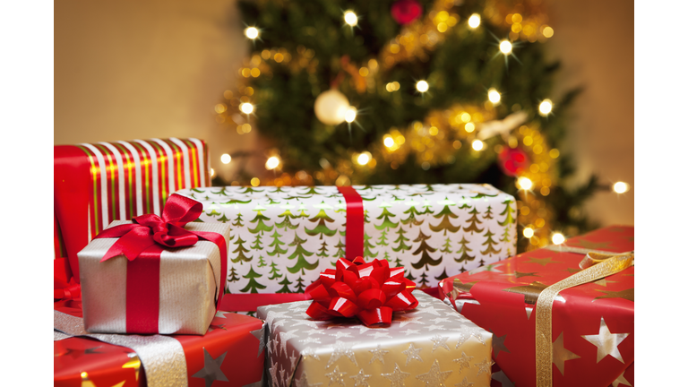 Group of Christmas gifts in front of tree.