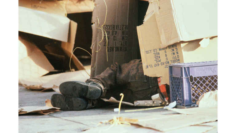 Feet of homeless person sleeping in cardboard box