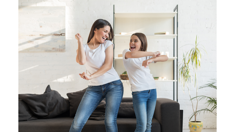 Mom with kid girl dancing in living room