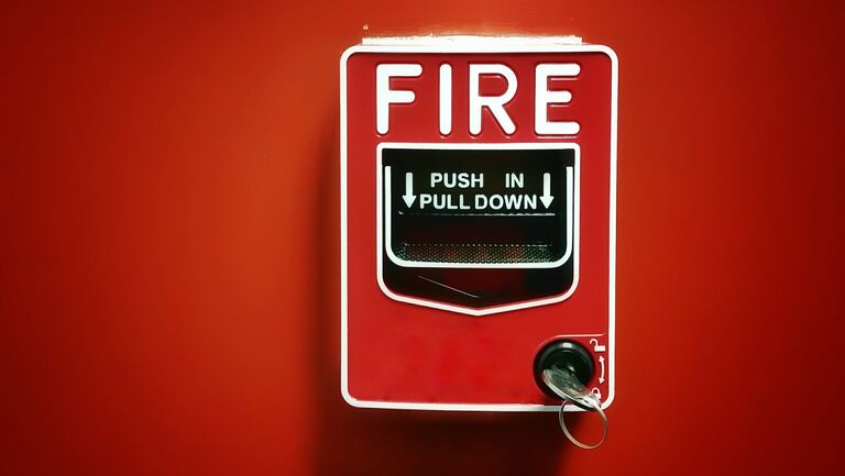 Close-Up Of Fire Alarm Box On Red Wall