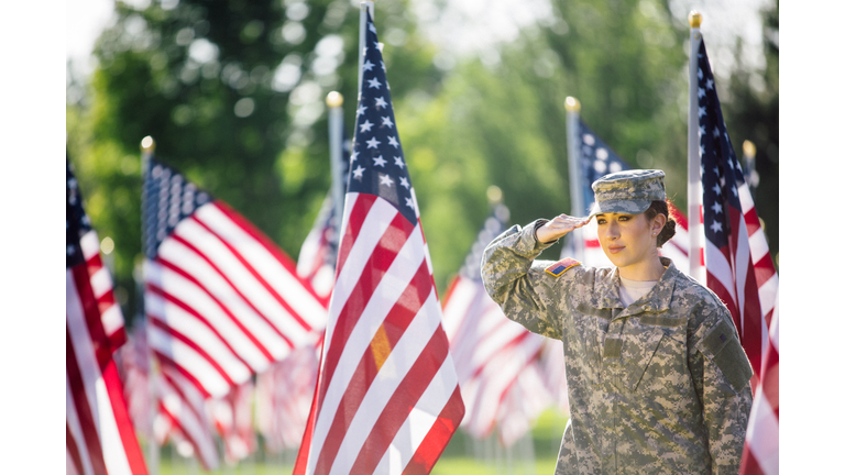 American Female Soldier saluting in front of American Flags