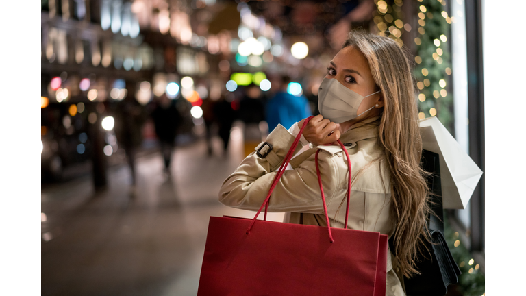 Happy woman Christmas shopping wearing a facemask