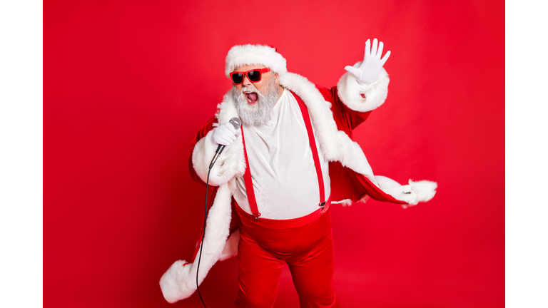 Portrait of cool funny fat overweight santa claus with big belly sing song on christmas party wear style stylish trendy eyeglasses eyewear hat isolated over red background