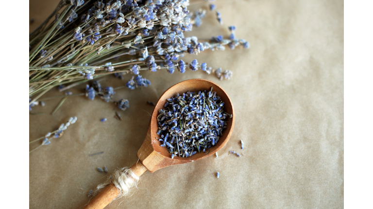 Wooden spoon with dried lavender flowers over craft brown background. Essential oil, organic natural ingredient for cosmetics, home and health care. Rustic style.