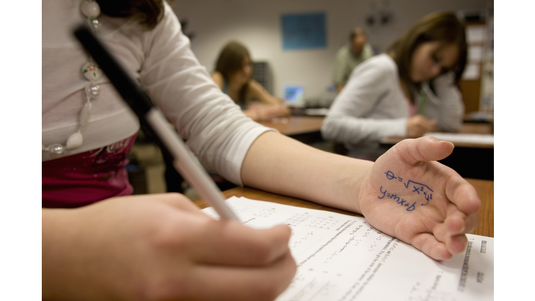 Teenage girl (15-17) cheating on math test (focus on formula on hand)