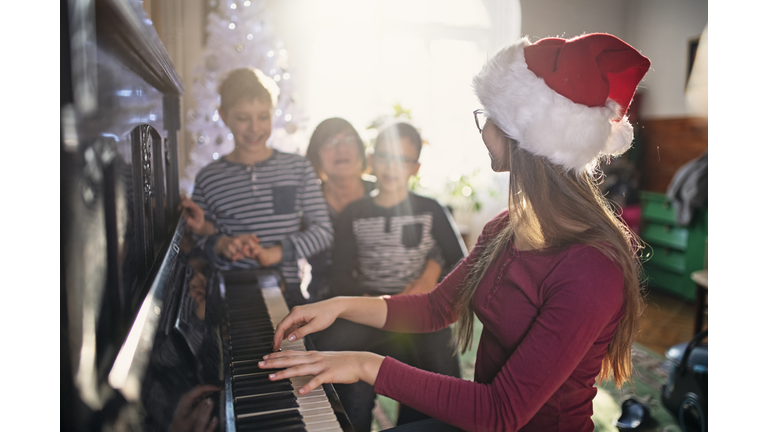 Teenage girl singing carols with family on Christmas