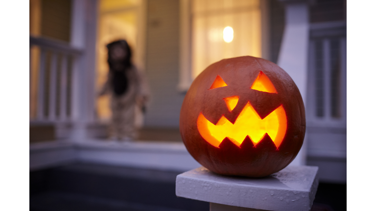 Close-up of jack o lantern with baby boy in background at dusk