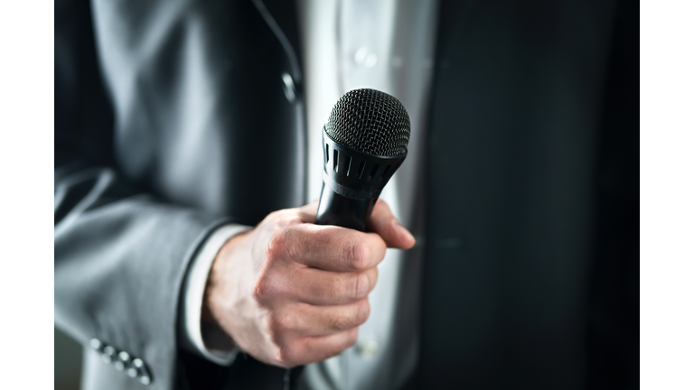 Business man holding microphone. Public speaking and giving speech in suit for audience concept. Fiance, host or best man giving toast with mic in wedding.
