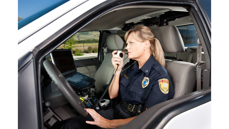 Female Police Officer Talking on Radio in Vehicle