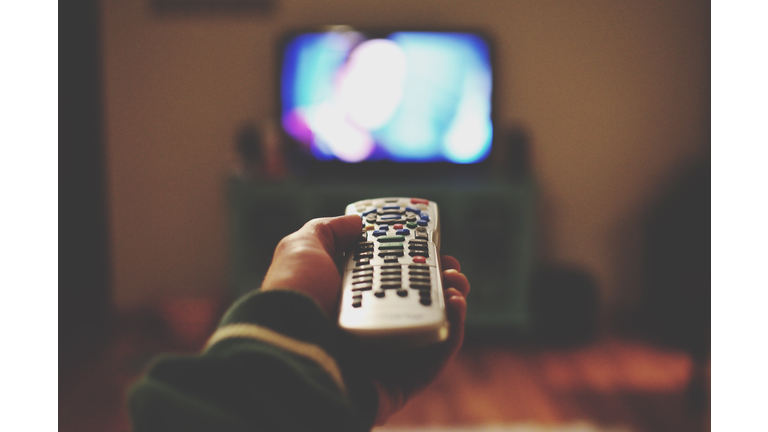 Cropped Of Person Holding Remote Control Against Television Set At Home