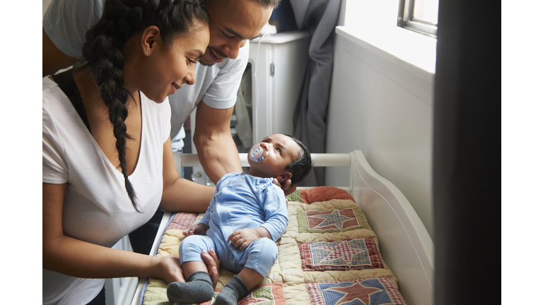 Couple laying newborn baby on changing table in nursery